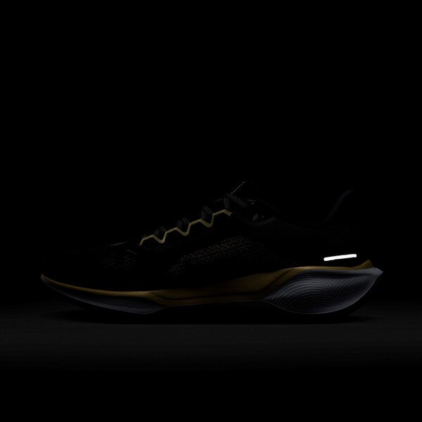 Side view of black Nike running shoe in the dark, showing reflective Swoosh, heel strip, and toe detail on white sole